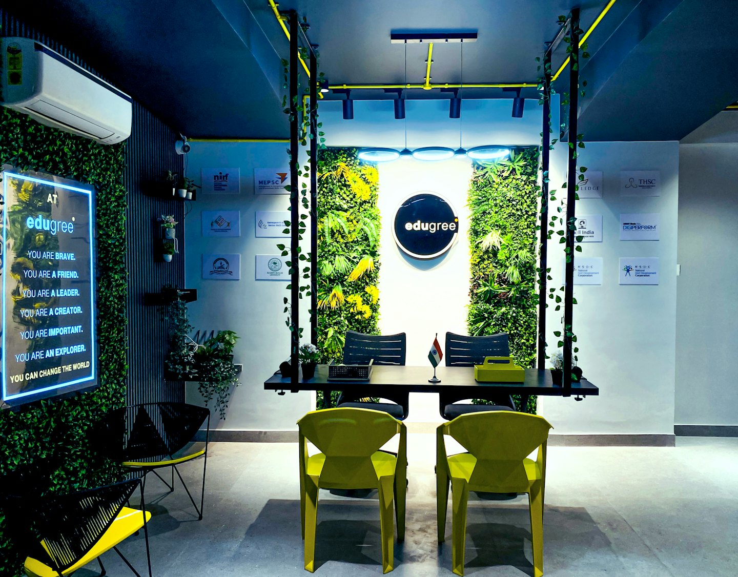 Modern office space with vertical gardens and yellow chairs.